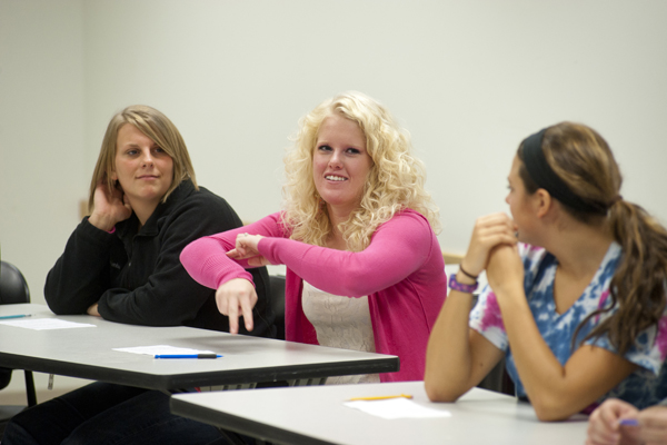 one student signing "midnight" while two other students watch